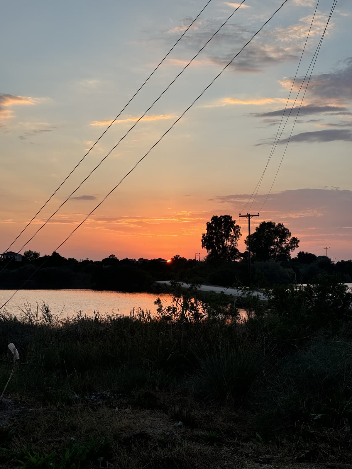 Rugged sunset with power lines over Koronisia